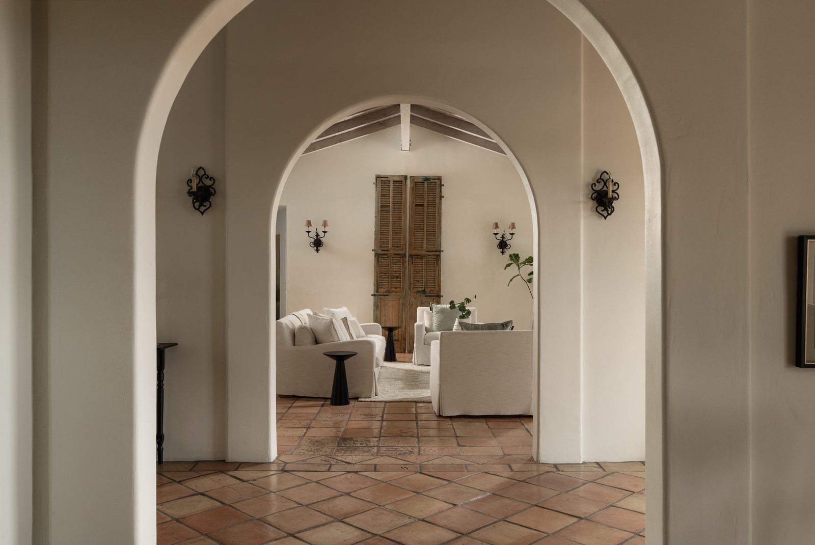 Arched entry opening to a terracotta-floored living room