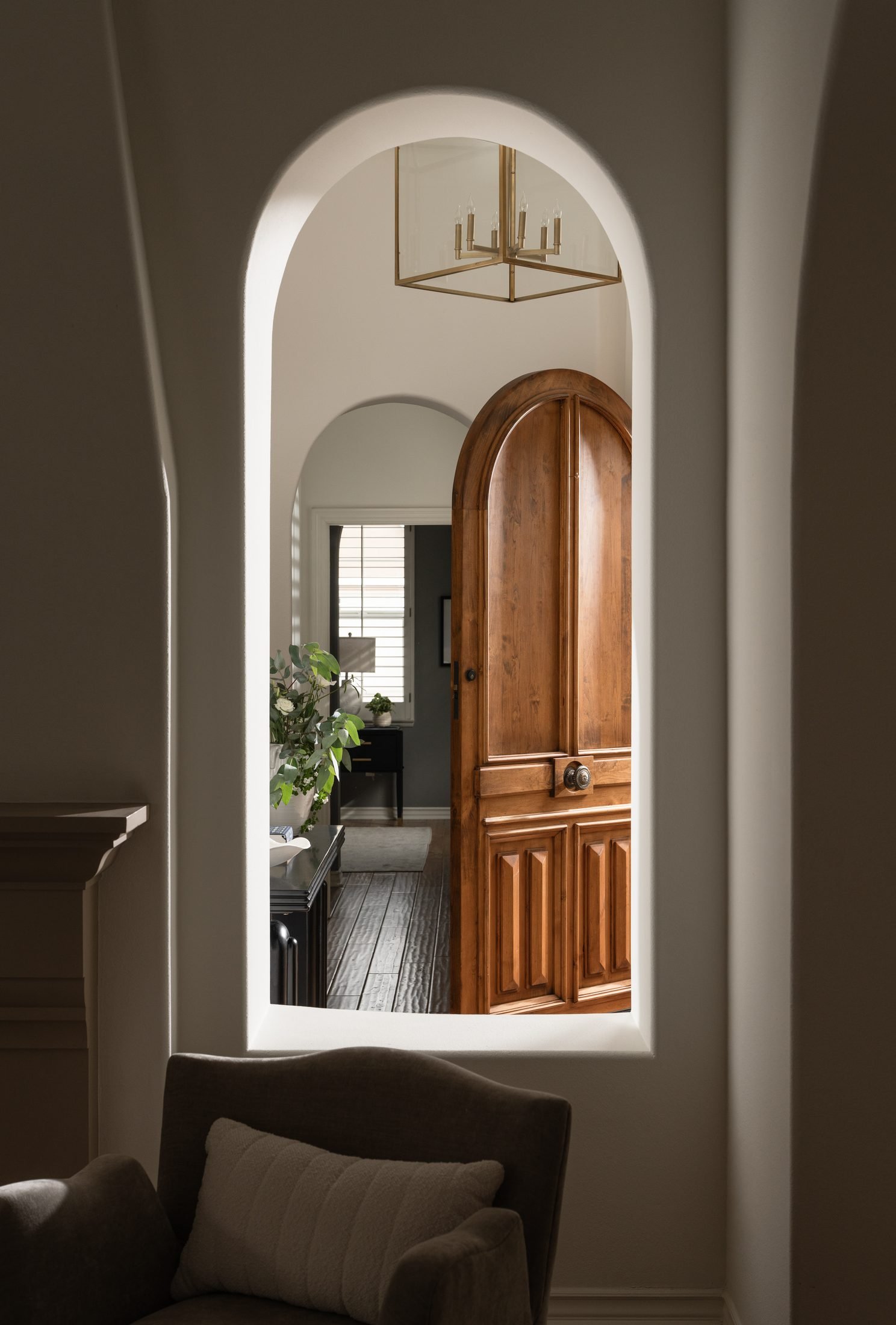 Arched hallway with a wood door by S & S Interiors