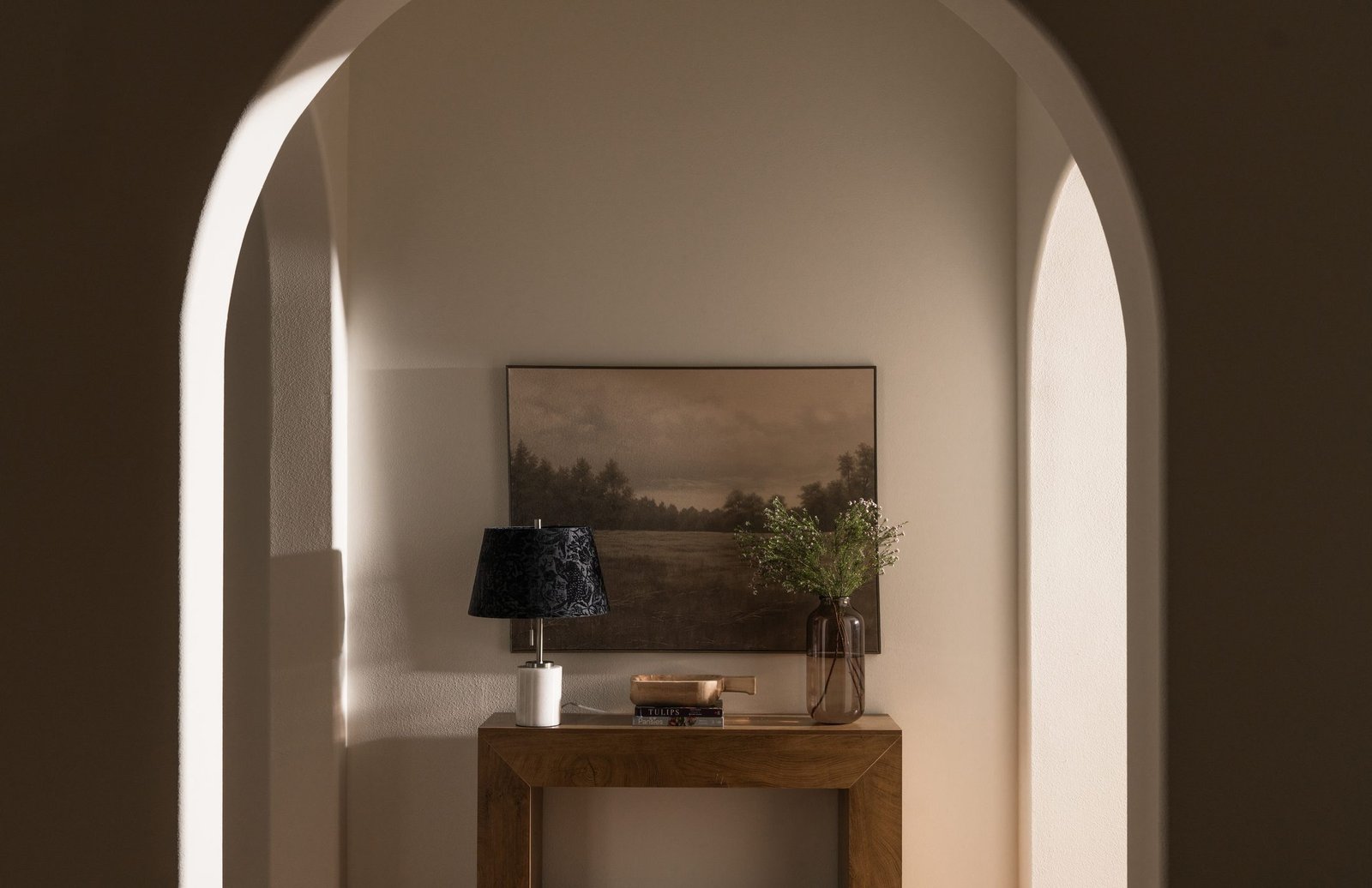 Arched niche with a console and landscape art, styled by S & S Interiors