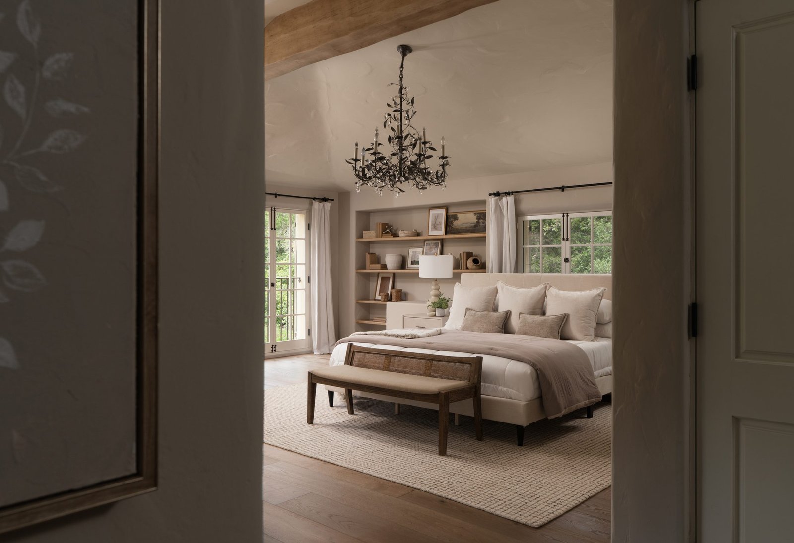 Serene bedroom with a chandelier and built-in shelving by S & S Interiors